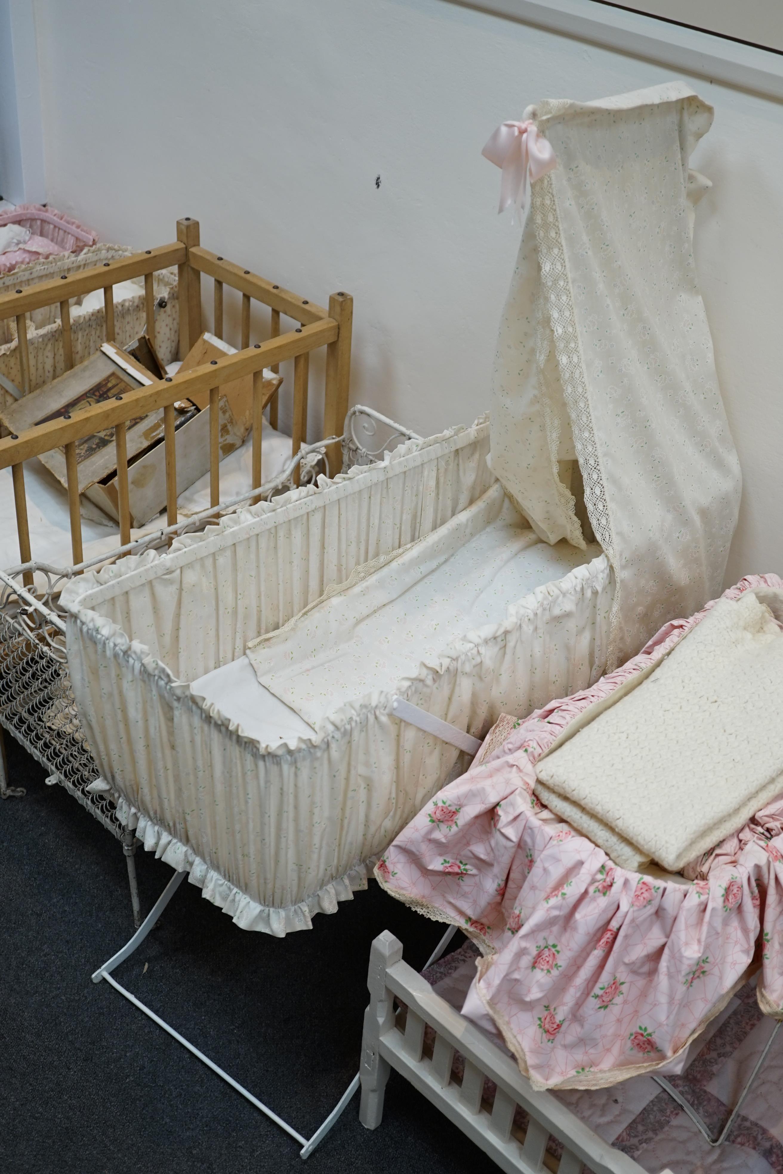 A collection of nine doll’s cribs of wood or wrought iron construction, together with two nineteenth century style doll’s ’bath chairs’, a toy mangle, Disney themed Snow White carpet sweeper and a boxed child’s sewing ma